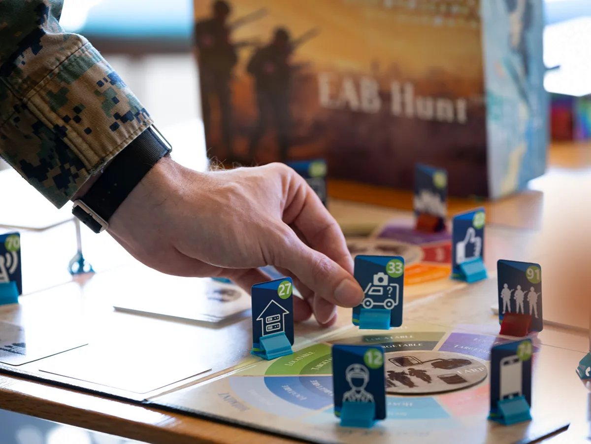 Hand in Marine Corps uniform plays a piece on a board game